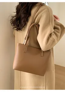 Vista dettagliata della borsa tote marrone in pelle con comodi manici e design minimalista.