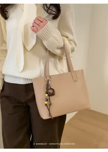 Vista dettagliata della borsa beige minimalista con ciondolo, elegante borsa da lavoro.