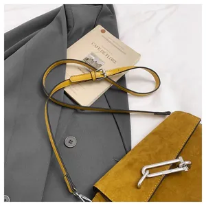 Detailed view of yellow suede cross body bag with metal clasp and thin strap, chic commute style.
