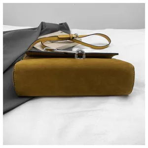 Yellow suede crossbody bag detail showing metallic hardware and texture, elegant style.