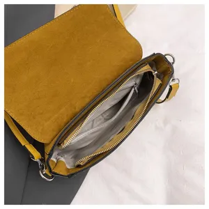 Detailed view of the yellow suede crossbody shoulder bag interior structure and zipper pockets.