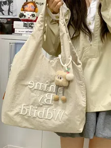 Details of casual beige canvas tote bag with stylish embroidery letter and cute plush keychain.