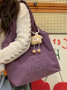 Detailed view of casual purple shoulder bag with cute plush pendant and stylish letter embroidery.