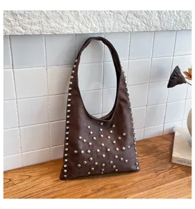 Stylish brown underarm shoulder bag decorated with metallic studs for a trendy punk look.