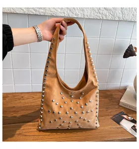 Close-up of brown suede shoulder bag with silver metal studs, stylish rivet hobo handbag.