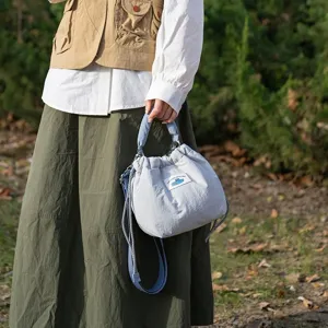 Light blue quilted camera bag detail showing drawstring closure and canvas label.