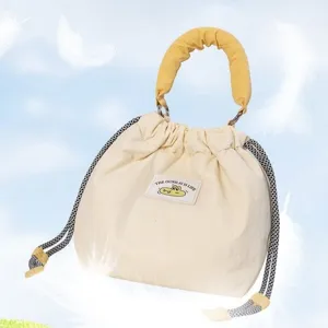 Close-up detail of quilted camera bag with yellow handle and cute cartoon label patch.