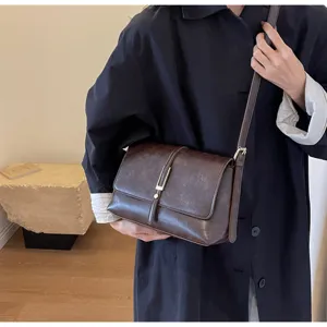 Detailed view of a retro brown shoulder bag with metal clasp and slim strap, autumn style.