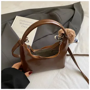 Vintage brown crescent shoulder bag for women, stylish hobo handbag with cute bear pendant.