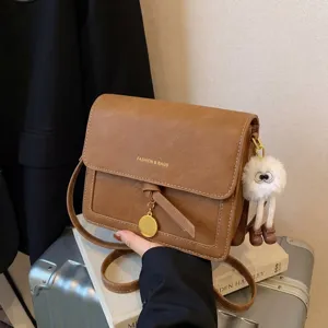 Detailed view of vintage brown crossbody bag featuring metallic ring and cute fluffy monster charm.