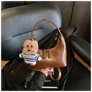 Vintage brown crescent shoulder bag featuring a cute plush bear pendant for daily commute.