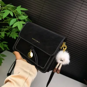 Classic black small shoulder bag with stylish stitching, gold pendant and cute plush toy.
