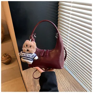 Vintage crescent shoulder bag for women, stylish leather hobo handbag with cute plush dog charm.