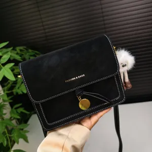 Detail view of black retro crossbody bag featuring white stitching and gold hardware.