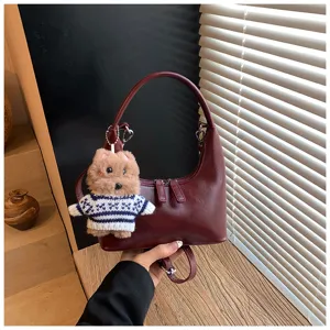 Dark red crescent leather handbag with cute bear plush keychain, retro commuting shoulder bag.