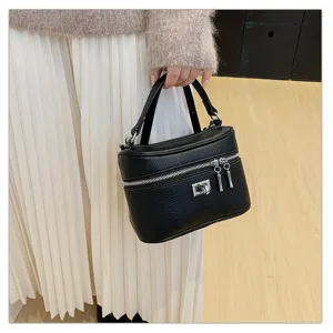 Detailed view of the black textured leather box handbag featuring metal lock and zippers.
