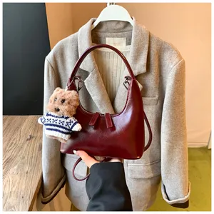 Retro dark red crescent shoulder bag detail with cute bear pendant and smooth zipper.