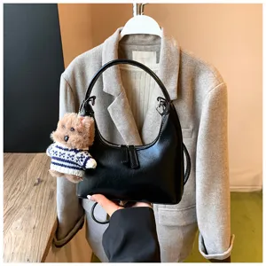 Trendy black crescent shoulder bag for women with cute plush dog charm, retro chic design.