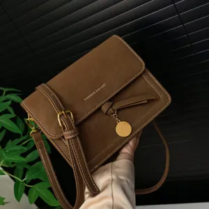 Retro brown leather shoulder crossbody bag with metal buckle and stylish round pendant detail.