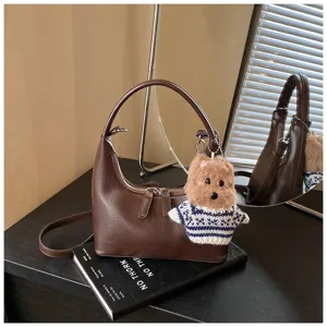 Retro crescent shoulder bag for women, stylish PU leather hobo handbag with plush keychain.