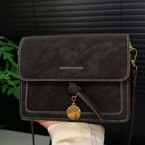 Retro brown leather crossbody bag detailed view showing texture, stitching and metal charm.