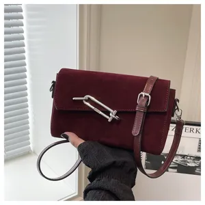 Elegant burgundy suede cross-body bag with chic metal lock closure and adjustable strap.