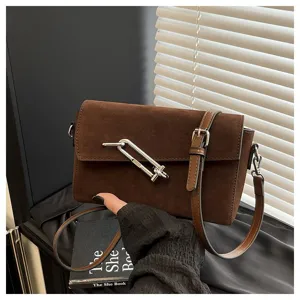 Close-up detail of the brown suede crossbody bag featuring a unique metal clasp and sleek strap.