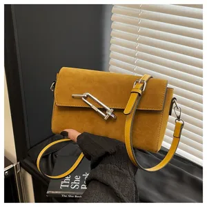 Close-up view of the yellow suede shoulder bag with metal lock detail and slim strap.