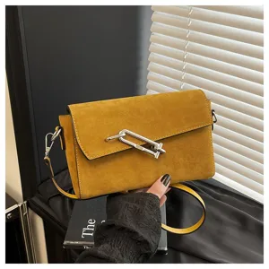 Detail view of a stylish yellow suede shoulder bag with unique metal hardware closure.