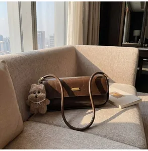 Close-up detail of the vintage brown leather baguette shoulder bag placed on a cozy sofa.
