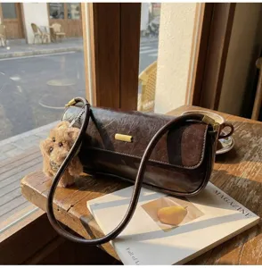 Brown textured baguette shoulder bag detail, close up view with cute plush bear pendant.