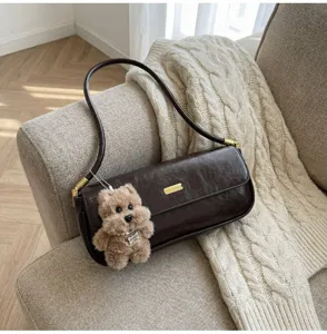 Detailed view of winter retro dark brown leather baguette shoulder bag with cute plush dog.