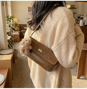 Retro brown baguette shoulder bag for women, chic PU leather purse with cute plush bear pendant.