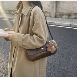 Detailed view of retro brown leather baguette shoulder bag featuring cute bear charm.