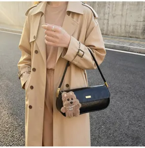 Detailed shot of a black PU leather baguette shoulder bag featuring a cute fluffy bear charm.