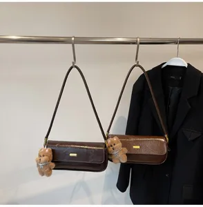 Retro brown patent leather baguette shoulder bag for women with cute plush bear pendant.