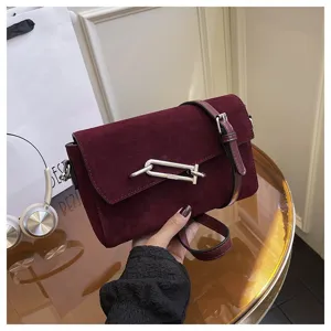 Detail shot of the wine red suede crossbody bag featuring a unique metal lock closure and strap.
