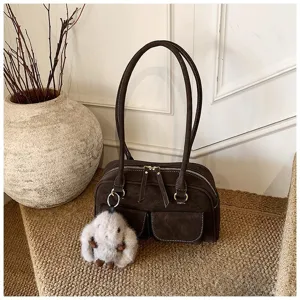 Detailed shot of retro brown suede shoulder bag with dual handles, front pockets and plush bunny charm.