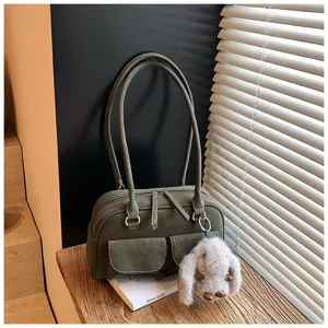 Retro dark green shoulder bag detail with dual handles, front pockets and plush bunny charm.