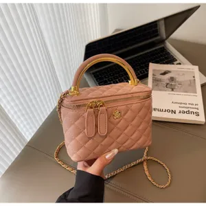 Close-up view of a chic pink quilted vanity bag with gold handle, chain strap, and flower accent.