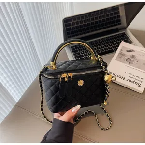 Black quilted vanity handbag with gold chain strap and elegant camellia flower charm detail.