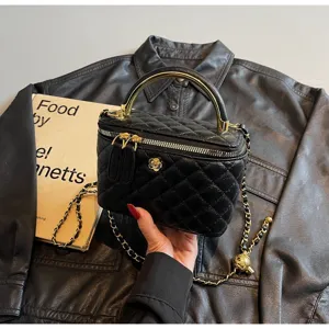 Classic black quilted leather vanity handbag with gold chain strap top handle and flower accent.