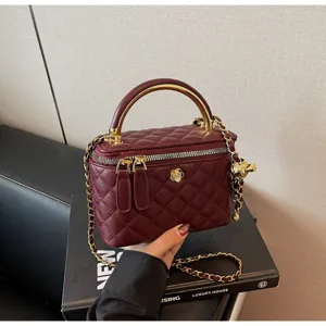Classic quilted vanity bag with metal handle and chain strap, elegant burgundy design detail.