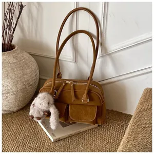 Brown retro shoulder bag with double handles, front pockets and cute plush bunny charm detail.