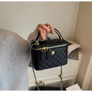 Detail view of a black quilted leather vanity handbag with gold chain strap and stylish lock.