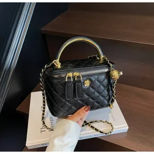 Close-up detail of the black quilted vanity bag with metal handle and elegant chain strap.