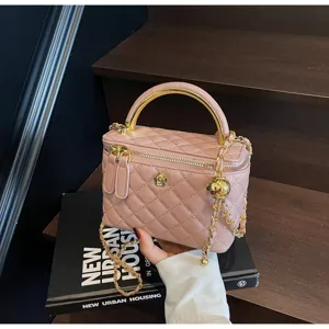Pink quilted vanity bag with metal top handle and gold chain strap, stylish detail view.