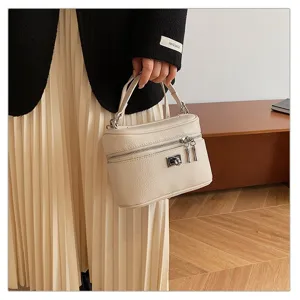 Detail view of a chic beige leather vanity handbag featuring a secure metallic lock and handle.