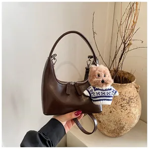Vintage brown crescent shoulder bag for women, stylish commuting handbag with cute plush dog charm.