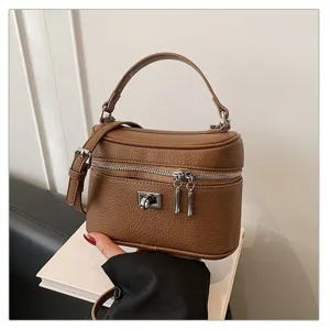 Close-up view of stylish brown leather vanity box bag featuring a top handle and zipper.